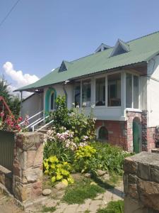 a house with a green roof and a garden at Лісова Пісня Апартаменти in Husyatyn