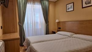 a hotel room with two beds and a window at Pensión La Concha in San Sebastián