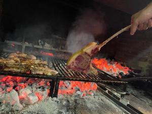 una persona está cocinando carne en una parrilla en Agriturismo Pettino, en Campello sul Clitunno
