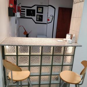 a kitchen with a counter with chairs and a refrigerator at Rosa Ramona Rooms in San Salvador de Jujuy