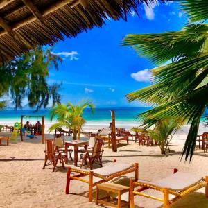una playa con mesas y sillas y un parque infantil en Simba Beach Zanzibar, en Kiwengwa