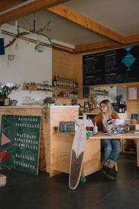 una mujer sentada en un mostrador en un restaurante con una tabla de surf en Maison Glaz, en Gâvres