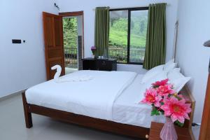 a bedroom with a bed and a swan in a vase with flowers at Peace Valley Home Stay in Munnar