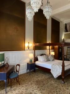 a bedroom with a bed and a desk and chandeliers at Langtry Manor Hotel in Bournemouth