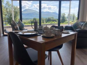 mesa de comedor con sillas y ventana grande en Stag Lodge en Spean Bridge