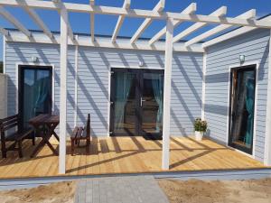 a house with a wooden deck with a pergola at Domki Portowe in Władysławowo