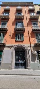拿坡里的住宿－Rosso Partenopeo Suite，一座橙色的大建筑,前面有一个拱门