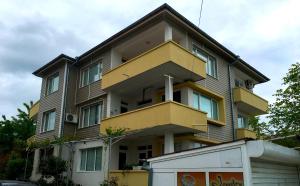 a yellow and brown building with a van in front of it at Къща за гости Германови in Obzor