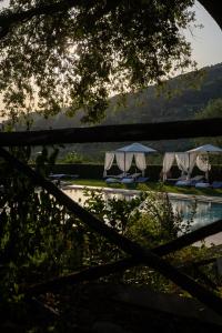 dos mesas con sombrillas junto a una piscina de agua en Borgo I Vicelli Adults Only Relais en Bagno a Ripoli