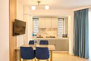 a kitchen with a wooden table and blue chairs at EEE Apart Boutique in Constanţa
