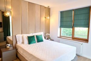 a bedroom with a large white bed with green pillows at EEE Apart Boutique in Constanţa