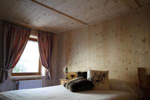 a bedroom with a bed with wooden walls and a window at Casa Sofia in Valdisotto