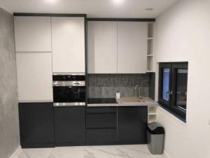 a kitchen with black and white cabinets and a sink at Domek na zaciszu in Szeligi