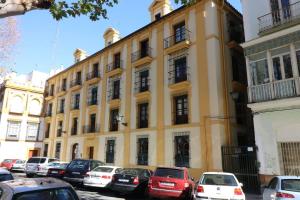un grand bâtiment jaune avec des voitures garées devant dans l'établissement Apartamento Cristo de Burgos - Kainga Homes, à Séville