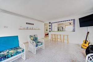 ein Wohnzimmer mit Stühlen, einem TV und einer Gitarre in der Unterkunft Hostal Palo Alto in San Andrés