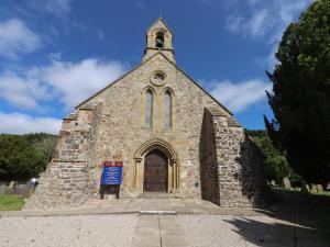 an old stone church with a clock tower and a door at The Poppy Fields Abode in Rhyl