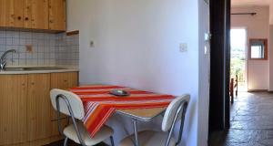 a kitchen with a table with chairs and a red and white towel at Aris Pension in Agia Paraskevi