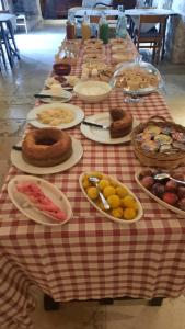 einem langen Tisch mit Teller mit Lebensmitteln auf einem roten und weißen Tischtuch in der Unterkunft Masseria Parco di Castro in Montalbano