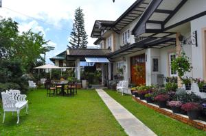 a house with a yard with white chairs and flowers at Cocoon Hills in Nuwara Eliya