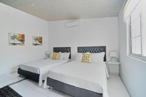 two beds in a bedroom with white walls and a window at Cabaña Palo Alto in San Andrés