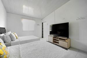 a white room with a television and a bed at Cabaña Palo Alto in San Andrés