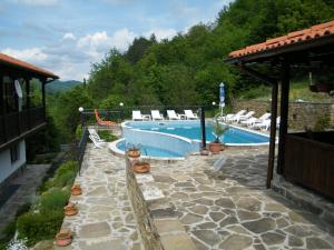 a swimming pool with chairs next to a house at Family Hotel Chiflik Hills in Chiflik