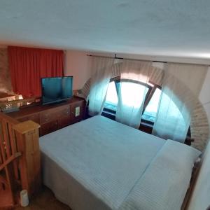 um quarto com uma cama, uma televisão e uma janela em Piazzetta Del Forno - Monolocale con Soppalco em Assergi