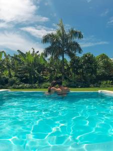 two people in a swimming pool with a palm tree at Apart-Hotel Garden Villa in Las Galeras