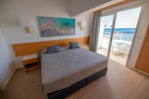 a bedroom with a bed with a view of the ocean at Tylos Beach Hotel in Kato Pyrgos