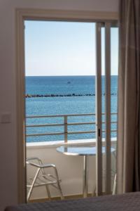 a room with a view of the ocean from a balcony at Tylos Beach Hotel in Kato Pyrgos
