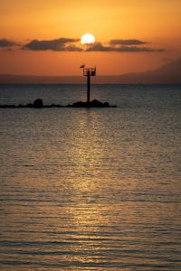 a cross on an island in the ocean at sunset at Tylos Beach Hotel in Kato Pyrgos