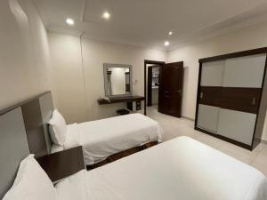 ein Hotelzimmer mit 2 Betten und einem Spiegel in der Unterkunft Al-Fakhamah Hotel Apartments - Families Only in Khobar
