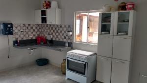 uma pequena cozinha com um fogão e um lavatório em Casa Condomínio Beira Rio em Canindé de São Francisco
