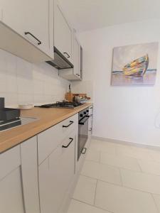 uma cozinha com electrodomésticos brancos e uma pintura na parede em Vitoria Apartment 1 em Mali Lošinj