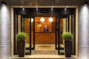 um homem parado na entrada de um edifício em Hotel Santa Costanza by OMNIA hotels em Roma