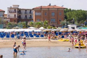 un grupo de personas en una playa con sombrillas en Hotel Villa Fulgida, en Cattolica