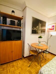 Habitación con mesa, TV y cama. en Sleeping Gran Via, en Madrid