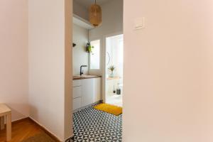 a bathroom with white walls and a hallway with a yellow rug at Bridge Studio in Chalkida