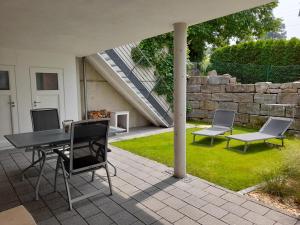 a patio with a table and chairs and a stone wall at Ferienwohnung im Weinbergweg in Ravensburg