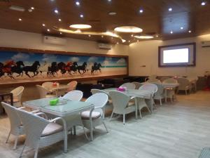 Corniche Palace Hotel في عجمان: غرفة طعام بها طاولات وكراسي وشاشة