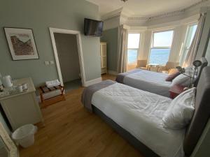 una camera d'albergo con due letti e una televisione di Rolling Wave Guesthouse a Bundoran