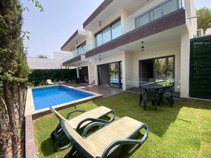 una casa con piscina y 2 sillas de césped en VILLA AMALOU AVEC PISCINE FAMILLE UNIQUEMENt en Agadir