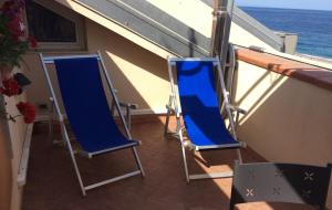 two blue chairs sitting on a balcony overlooking the ocean at Casa Vacanze Samira in Fondachello