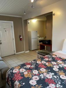 a bedroom with a bed and a kitchen with a refrigerator at Motel Safreen in Panama City Beach