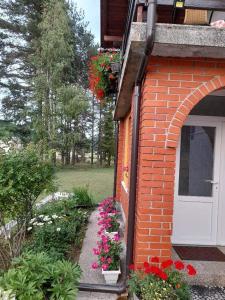 un jardín con flores junto a un edificio de ladrillo en Rooms Danica en Donji Babin Potok