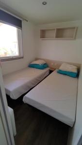 two beds in a small room with a window at MOBIL HOME camping **** Canet en Roussillon in Canet-en-Roussillon