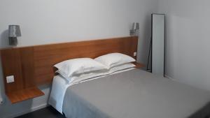 un letto con lenzuola e cuscini bianchi in una stanza di Angra Downtown ad Angra do Heroísmo