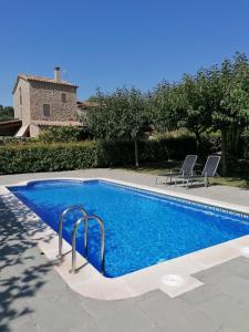 una piscina con 2 sillas y una casa en Casa Cabots, en Olvan