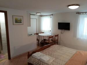 - une chambre avec un lit, une table et une télévision dans l'établissement Apartments Ivanis, à Vrsar