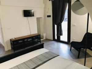 a bedroom with a bed and a tv and a chair at La Grotta di benikula' in Pantelleria